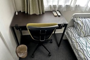 A room with a desk, a chair, a bed, a window with curtains, and a remote control on the desk. - Warmhome-hirai2F (Tokyo)