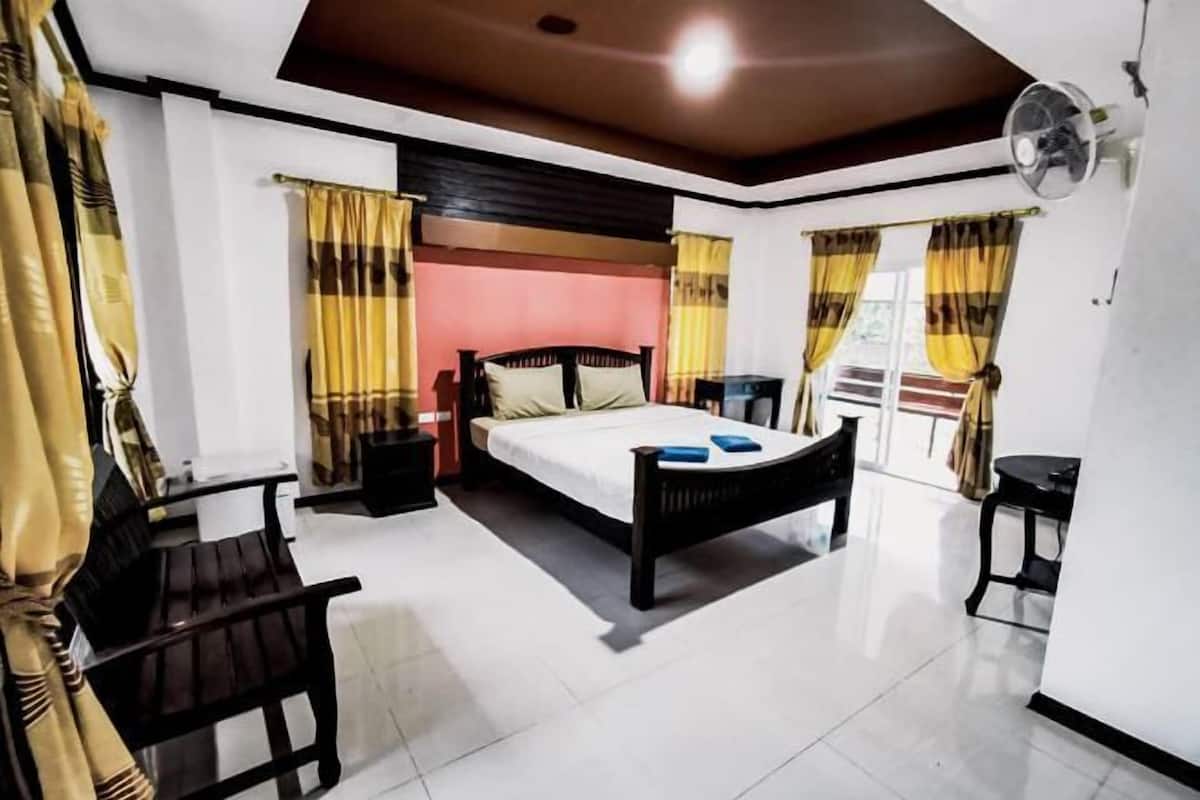 A bedroom with a bed, bedside tables, a desk, and a chair.