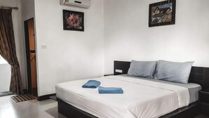 A bedroom with a bed, a headboard, a window with curtains, and two wall-mounted paintings.