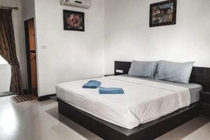 Une chambre à coucher comprenant un lit, une tête de lit, une fenêtre avec des rideaux et deux tableaux accrochés au mur.