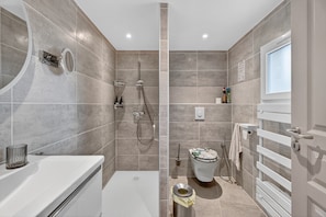 Un baño moderno con bañera, ducha, inodoro y ventana.