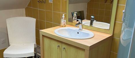 A bathroom with a white sink, wooden cabinets, a mirror, and a checkered floor.