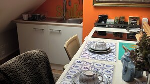 A dining area with a table set for two, a kitchen in the background, and a painting on the wall. - Large, comfortable room, parking spaces, pets welcome, bicycle garage (Étaples)
