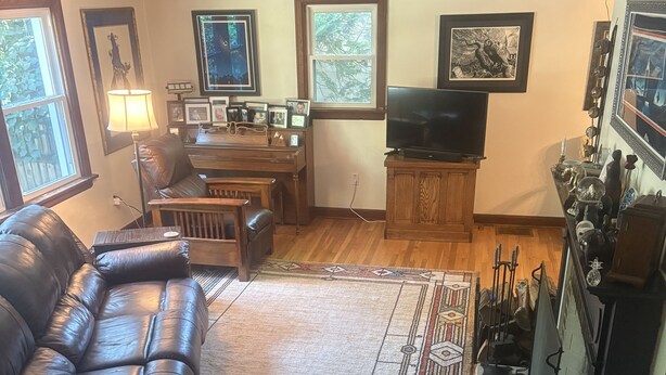 Ein Wohnzimmer mit einer Ledersofa, einem Holztisch, einem Fernseher und gerahmten Bildern an der Wand.