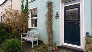 A townhouse with a blue door, a white bench, and a sign reading "Cledan". - Cottage close To Coastal Path & Puffin Island | Pass the Keys (Beaumaris)