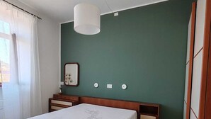 A bedroom with a large bed, bedside tables, a nightstand, a hanging light fixture, and a green accent wall. - LA CASINA Panoramic apartment in the countryside very close to the village (Amelia)