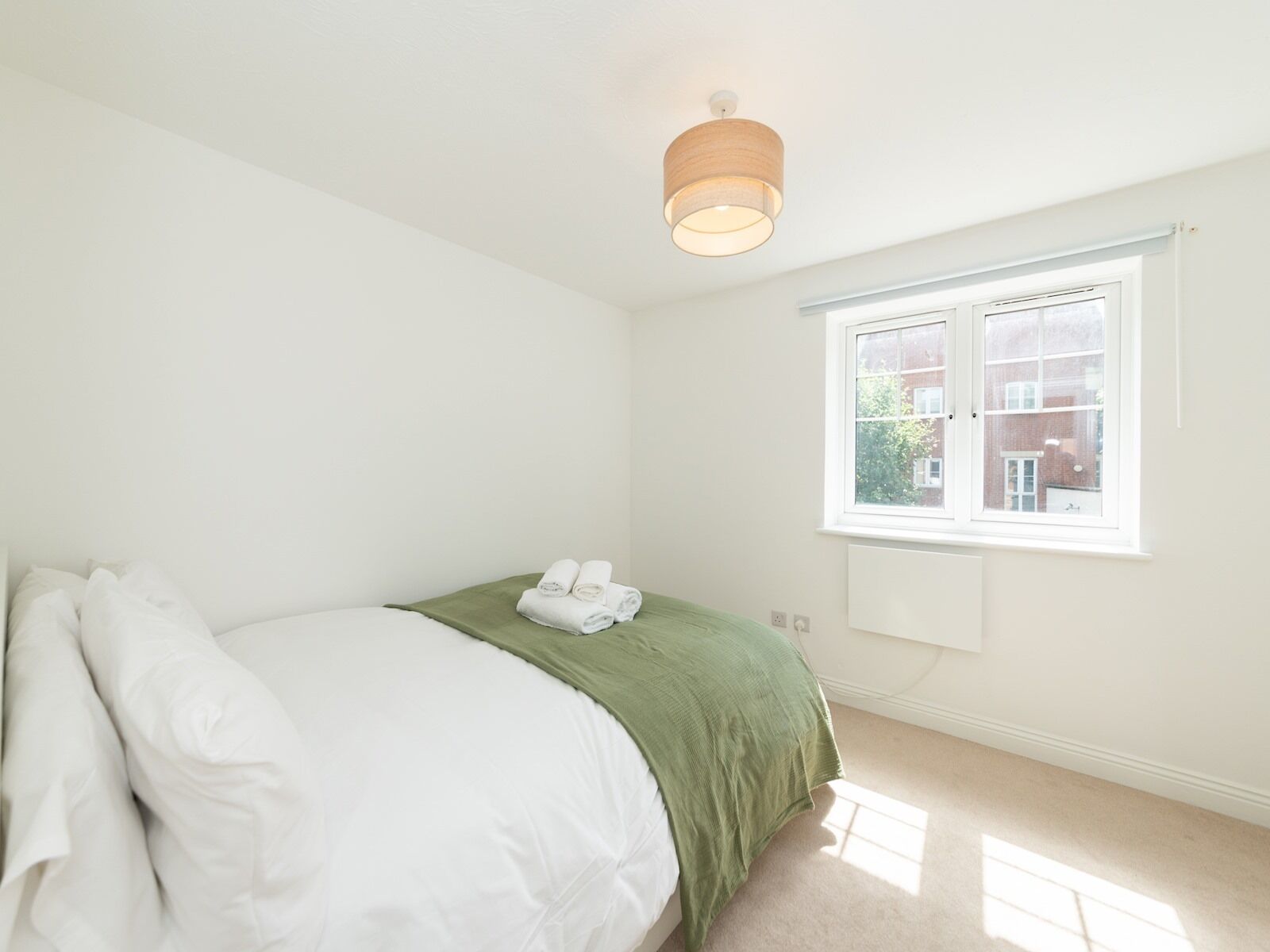 A bedroom with a bed, a window, and a ceiling light.