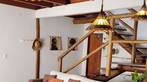 Un rincón acogedor con un banco de madera, un sofá con cojines y una mesa de madera con frutero.