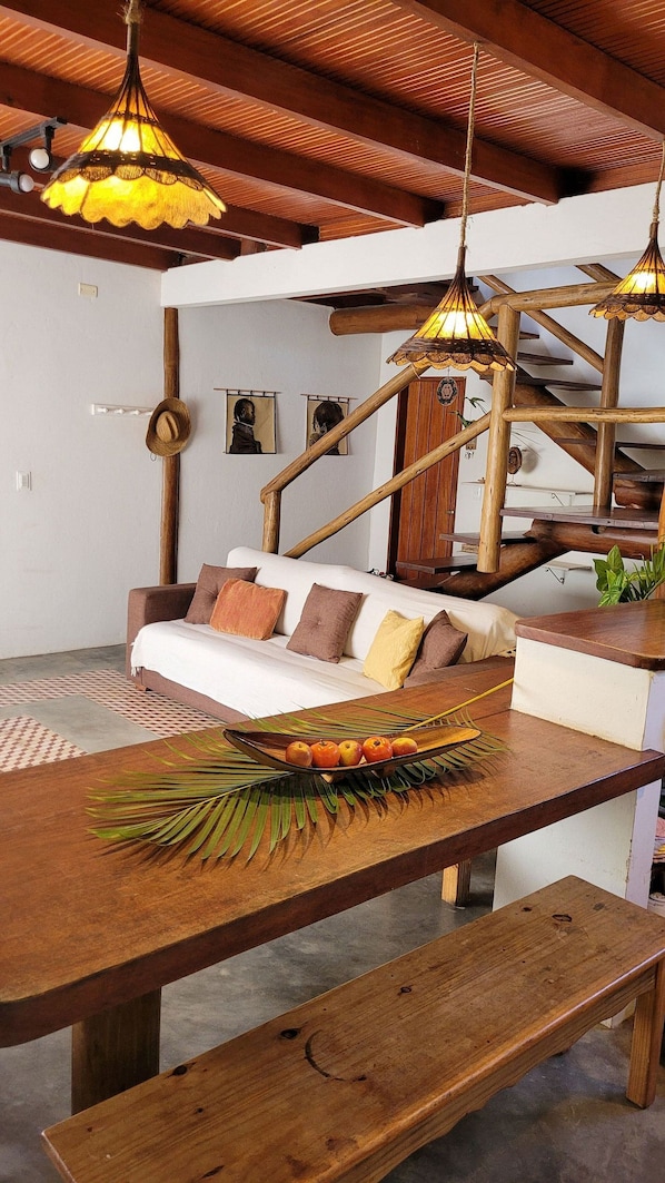 A cozy living area with a wooden bench, a sofa with cushions, and a wooden table with a fruit bowl.