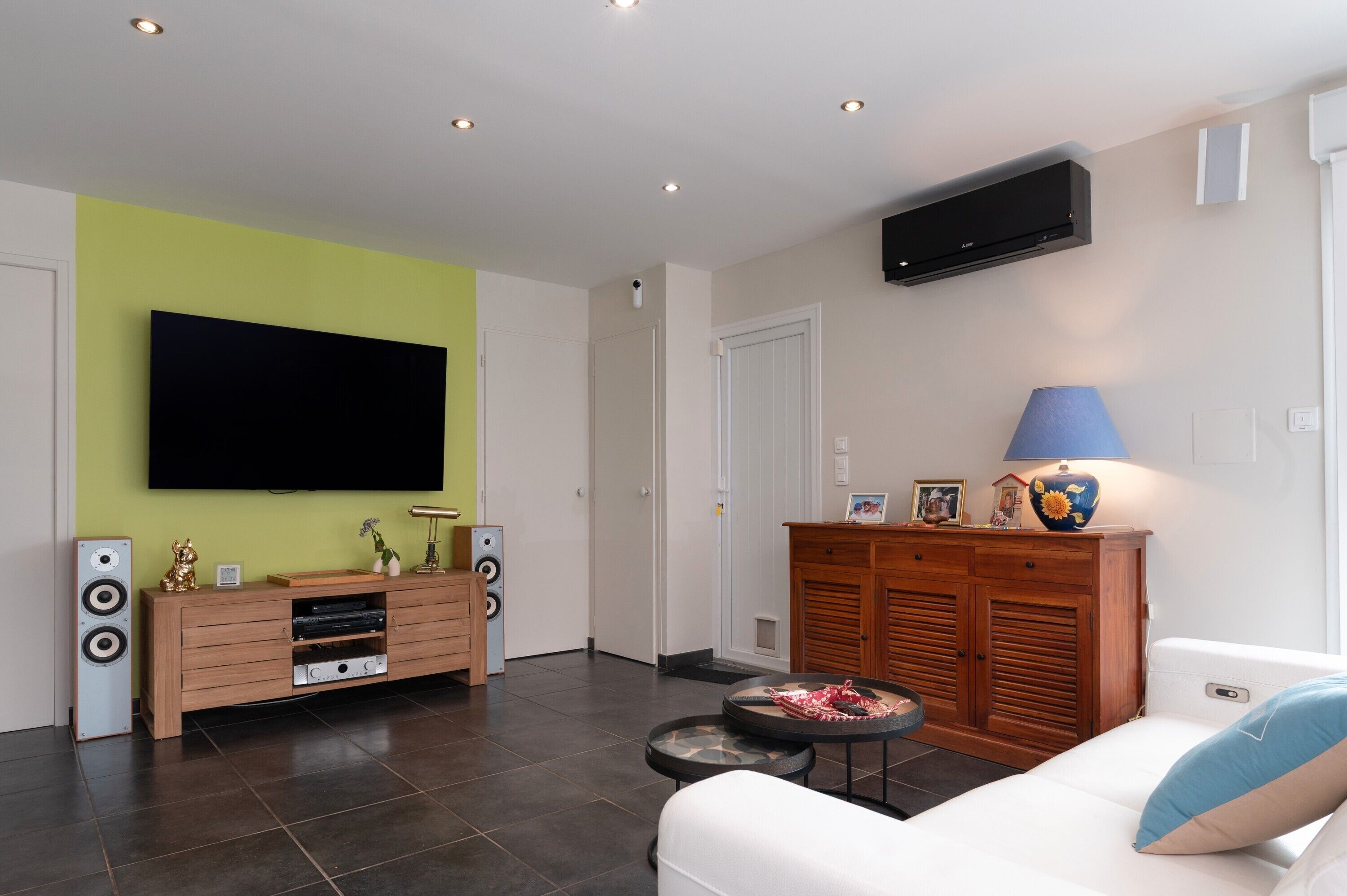 Ein Wohnzimmer mit Flachbildfernseher, einem Holzkasten, einer Couch und einer Lampe.