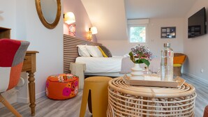 A bedroom with a bed, bedside lamps, a mirror, a television, and a window.