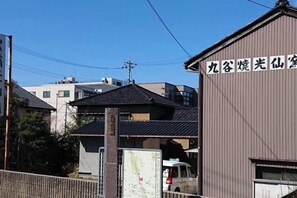 A building with a sign in Japanese, a parked van, and a fence. - kanazawakigen (Kanazawa)