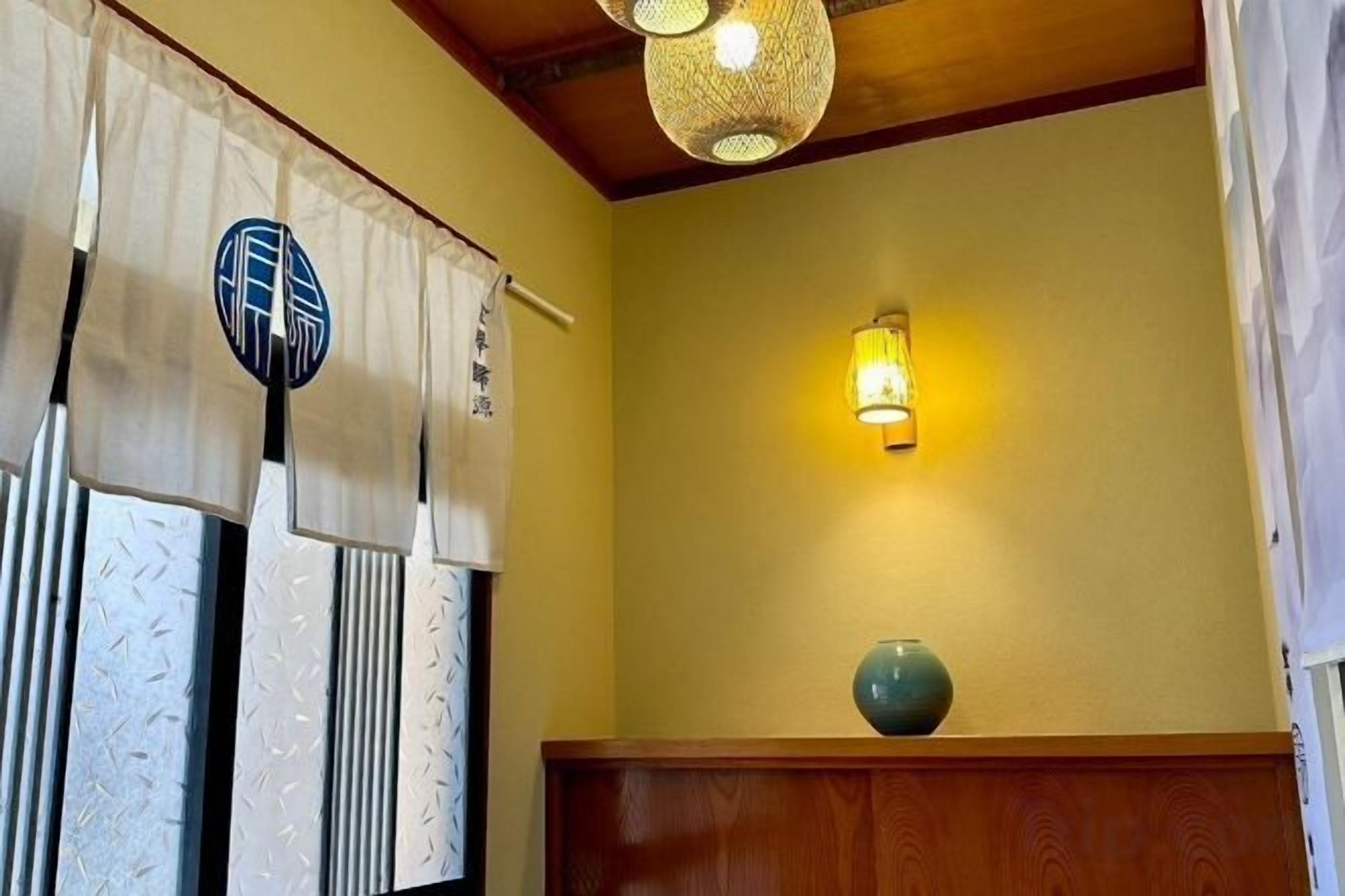 A room with a traditional Japanese shoji screen, a hanging lantern, and a wooden bench.