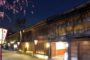 Un edificio japonés tradicional con fachadas de madera y ventanas iluminadas por la noche.