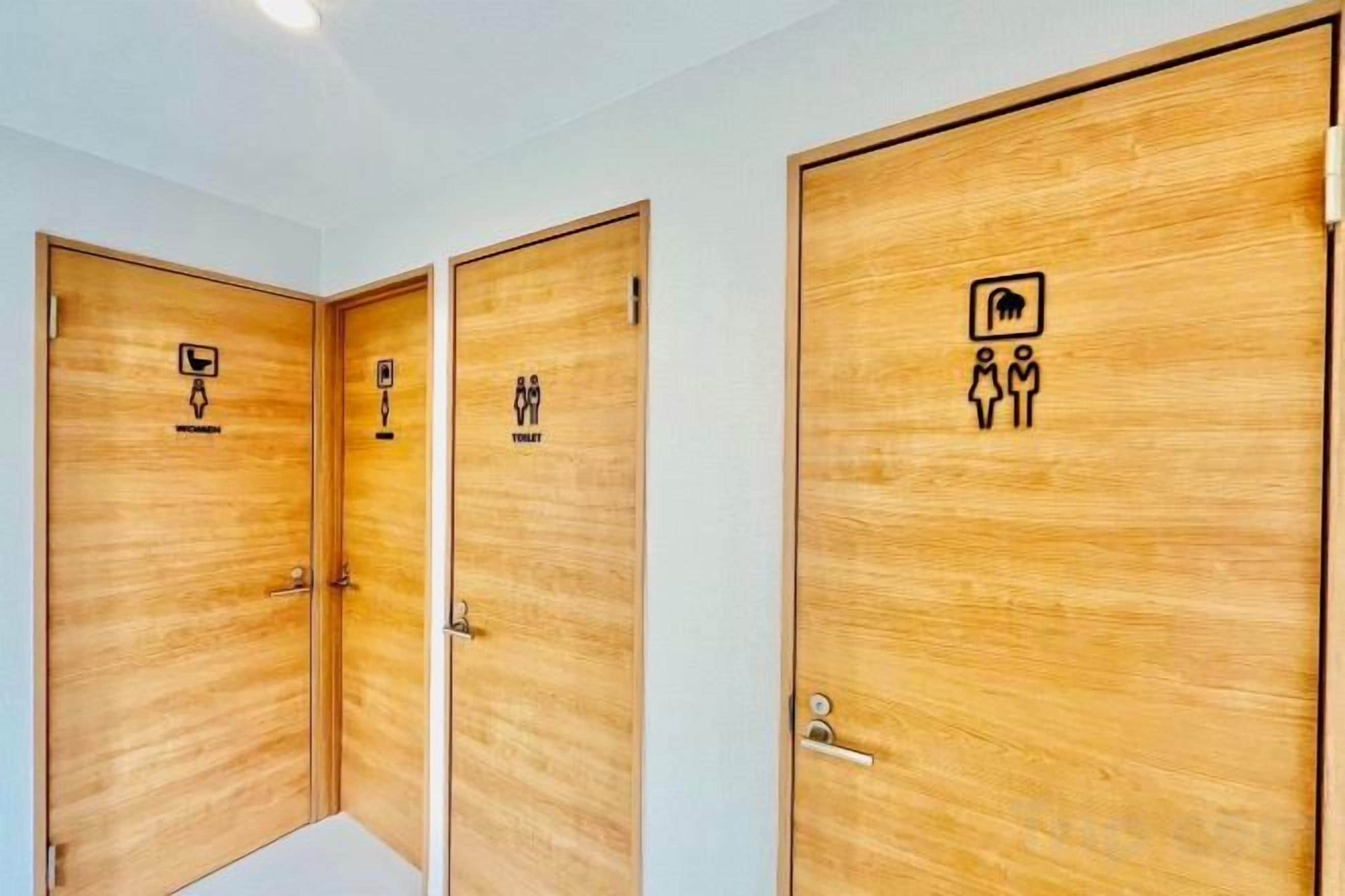 A set of wooden doors with restroom symbols indicating facilities for men, women, and a family room.