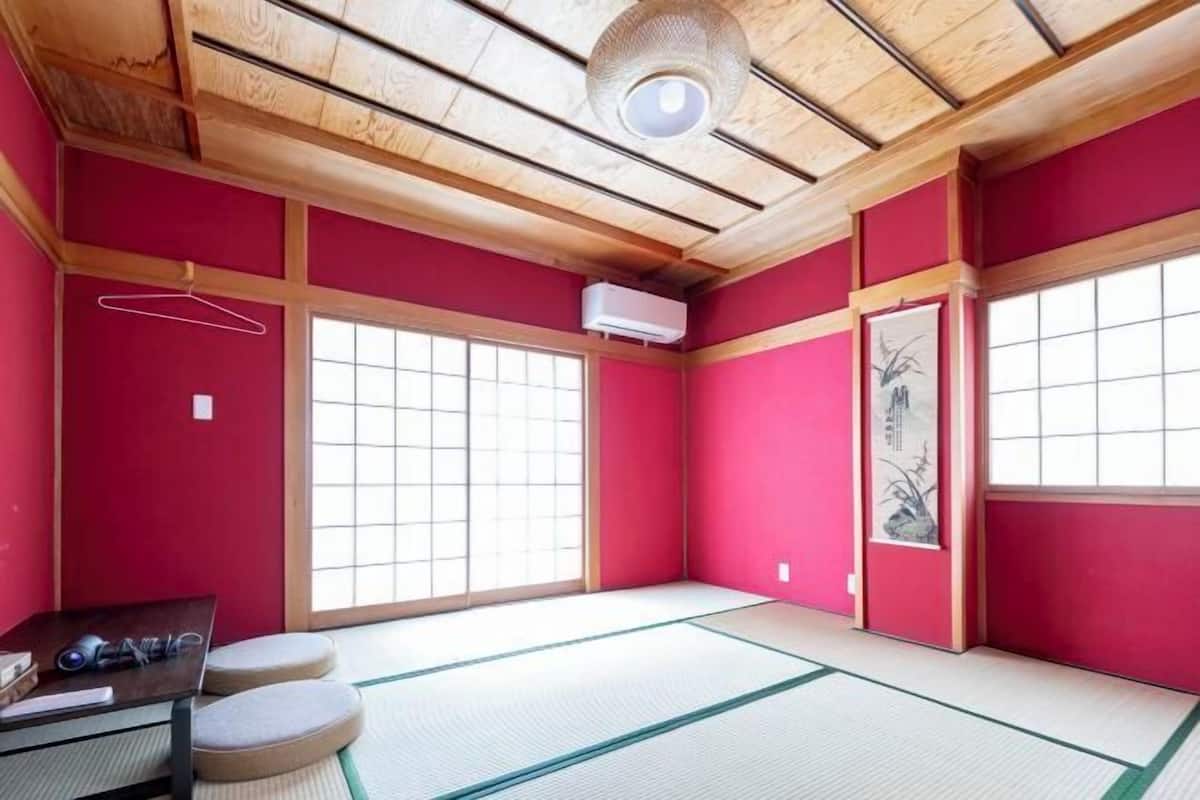 A tatami mat room with a wooden ceiling, a tatami mat table, a tatami mat bench, and a sliding door.