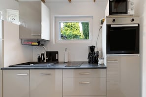 Una cocina moderna con ventana, microondas integrado y cafetera.
