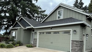 Une maison à deux étages avec un garage, des éléments décoratifs en pierre et une pelouse bien entretenue.