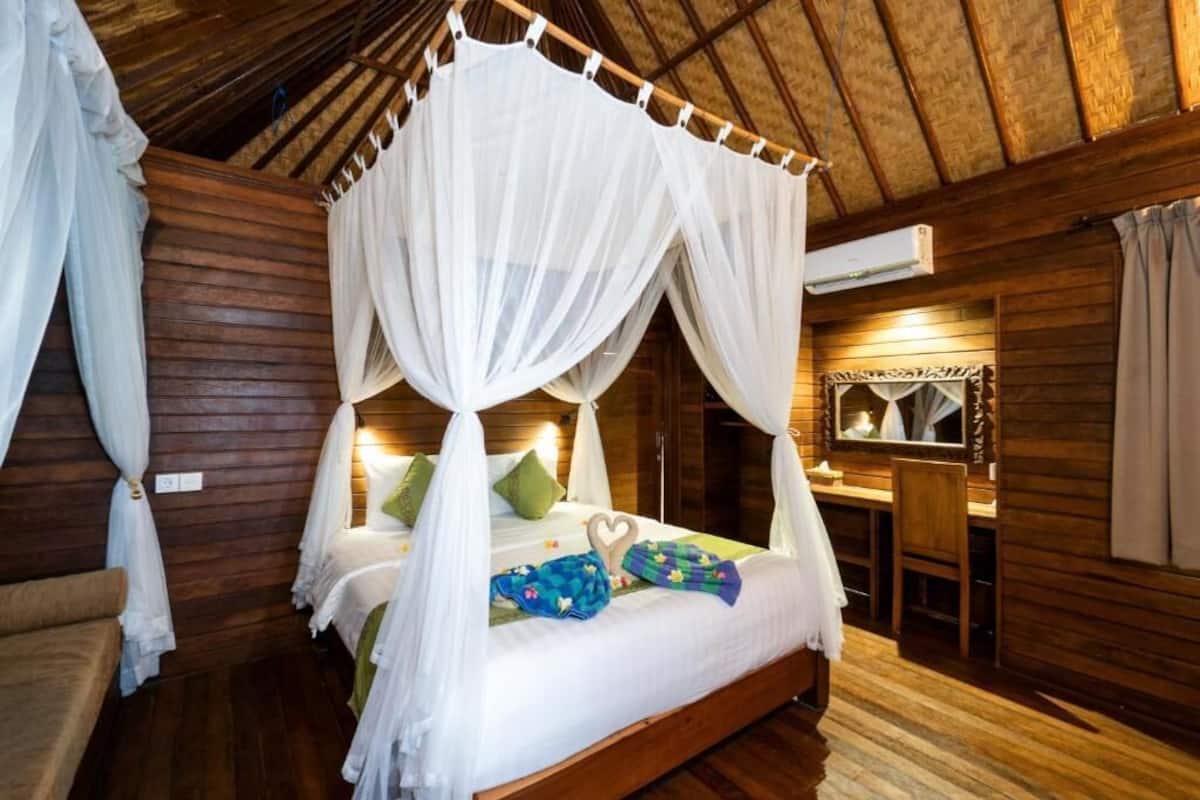 Ein Zimmer in einer Holzhütte mit einem Himmelbett, einem kleinen Schreibtisch und einem Spiegel.