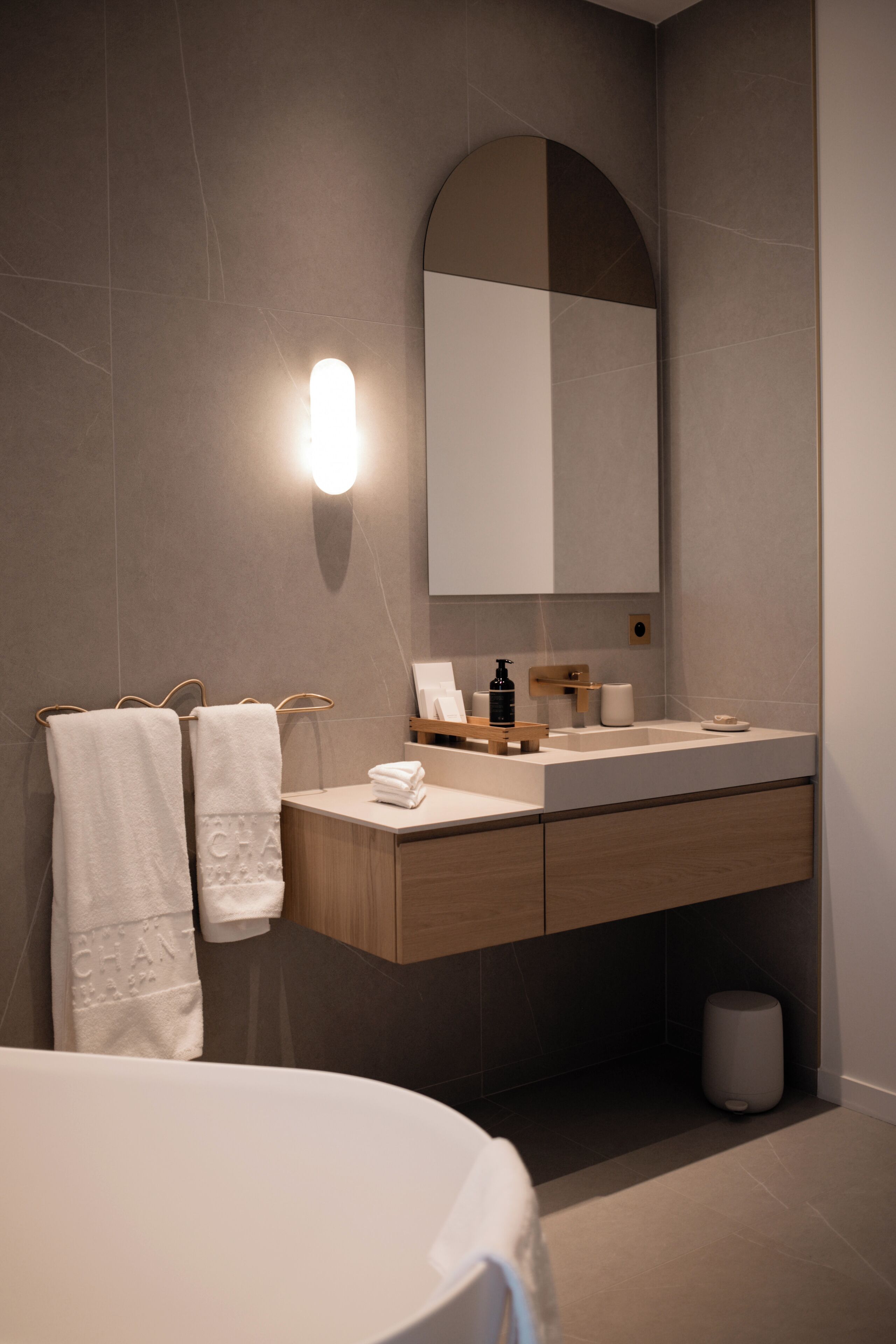 A modern bathroom with a wooden vanity, a large mirror, and a white sink.