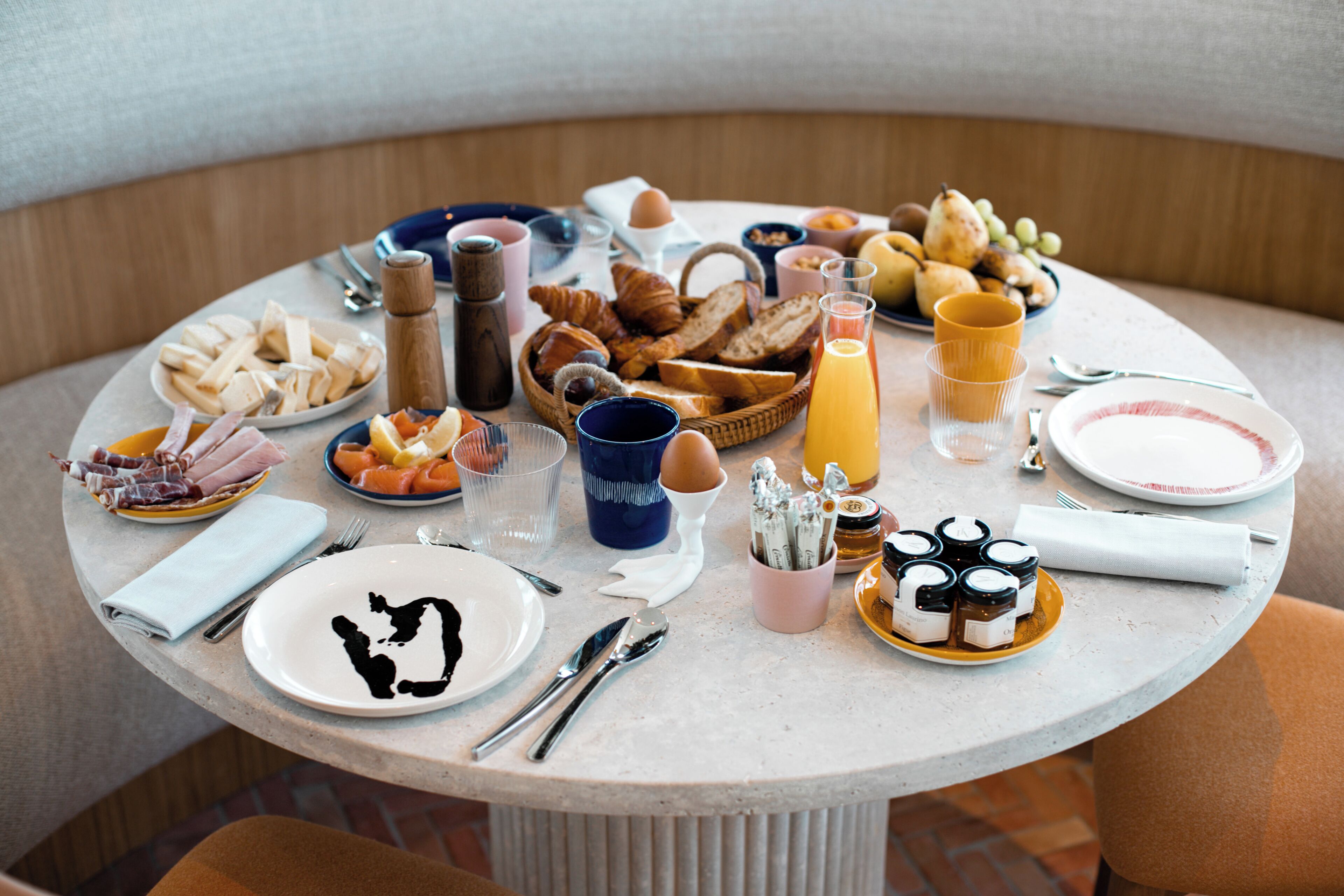 Una mesa redonda de comedor con diversas opciones de desayuno, como pasteles, frutas y bebidas.