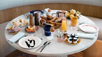 Una mesa redonda de comedor con diversas opciones de desayuno, como pasteles, frutas y bebidas.