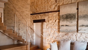 A modern interior with a stone wall, a wooden staircase, and a sofa with cushions. - La Maison Verchant (Montpellier)