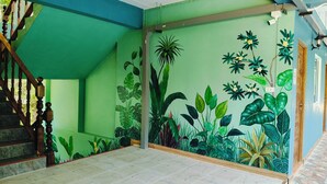 A staircase with wooden balusters leading to a green-walled room with a tropical mural. - Makorn Nonkleng (Thung Song)