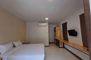 Una habitación de hotel con cama, escritorio, televisor y armario.