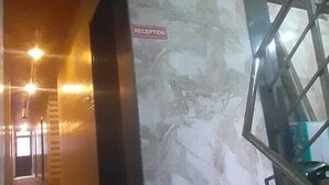 En reception med en marmorvæg, et receptionsskrivebord og en trappe til en etage ovenover.