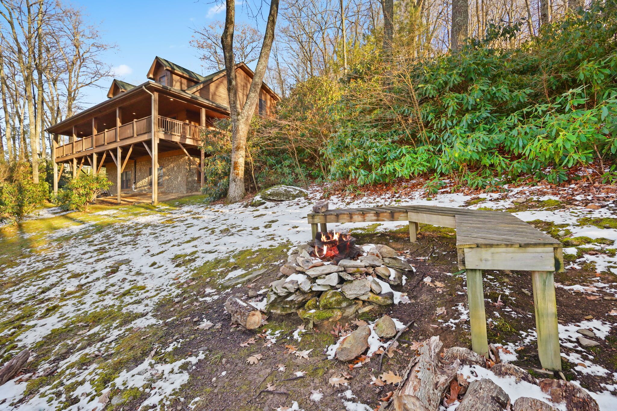 A cabin with a wooden deck and a stone fire pit.