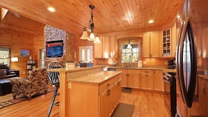 A wooden cabin interior with a kitchen, dining area, and living room.