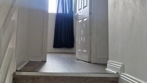 A hallway with a carpeted staircase leading to a room with a door and a window with a blue curtain. - Cork Apartment With River Views -cosy in Cork (Cork)