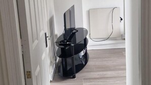 A hallway with a white door, a black entertainment unit, and a white radiator. - Cork Apartment With River Views -cosy in Cork (Cork)