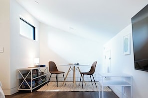 A modern room with a round table, two chairs, a bookshelf, and a flat-screen TV mounted on the wall. - *NEW Central Austin | Sleeps 12 - WalkerVR Firefly (Austin)