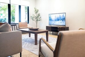A living room with a sofa, a coffee table, and a television on a stand. - *NEW Central Austin | Sleeps 12 - WalkerVR Firefly (Austin)