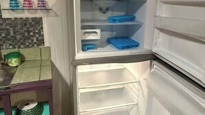 An open refrigerator with a blender on top, a tiled backsplash, and a small table with a green mat. - Air conditioned home w/ full kitchen, TV & parking (Puerto Viejo de Talamanca)