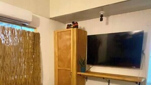 A bedroom with a bed, a wardrobe, a television, and a window with curtains. - Air conditioned home w/ full kitchen, TV & parking (Puerto Viejo de Talamanca)