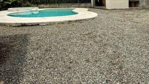 A swimming pool with a red-tiled roof structure in the background, surrounded by gravel. - 2 bed, 2 bath, full kitchen. With pool & parking. (Puerto Viejo de Talamanca)