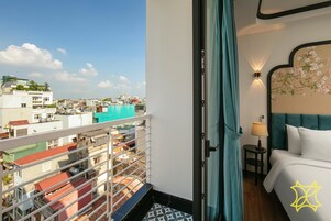 Een hotelkamer met balkon, een bed, nachtkastje en een wandlamp.
