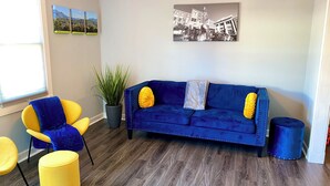 A living room with a blue sofa, yellow armchairs, and a potted plant.