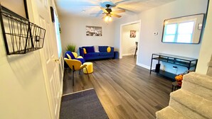 A modern living room with a blue sofa, yellow chairs, and a glass coffee table.