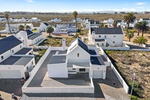 Zona residencial con casas blancas modernas, algunas con techos inclinados, y palmeras.