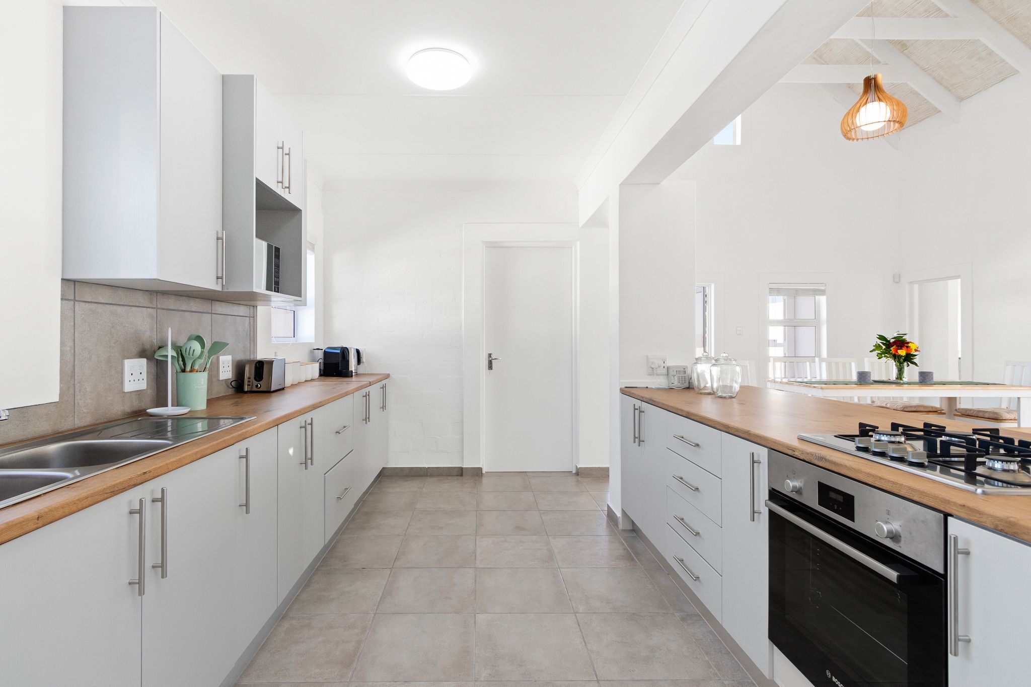 Una cocina moderna con armarios blancos, electrodomésticos de acero inoxidable y encimera de madera.