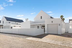 A modern white building with a garage, solar panels, and a paved driveway.