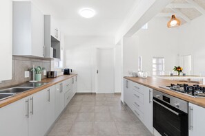 Una cocina moderna con armarios blancos, electrodomésticos de acero inoxidable y encimera de madera.
