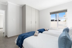 A hotel room with two beds, a wardrobe, and a window with a view.
