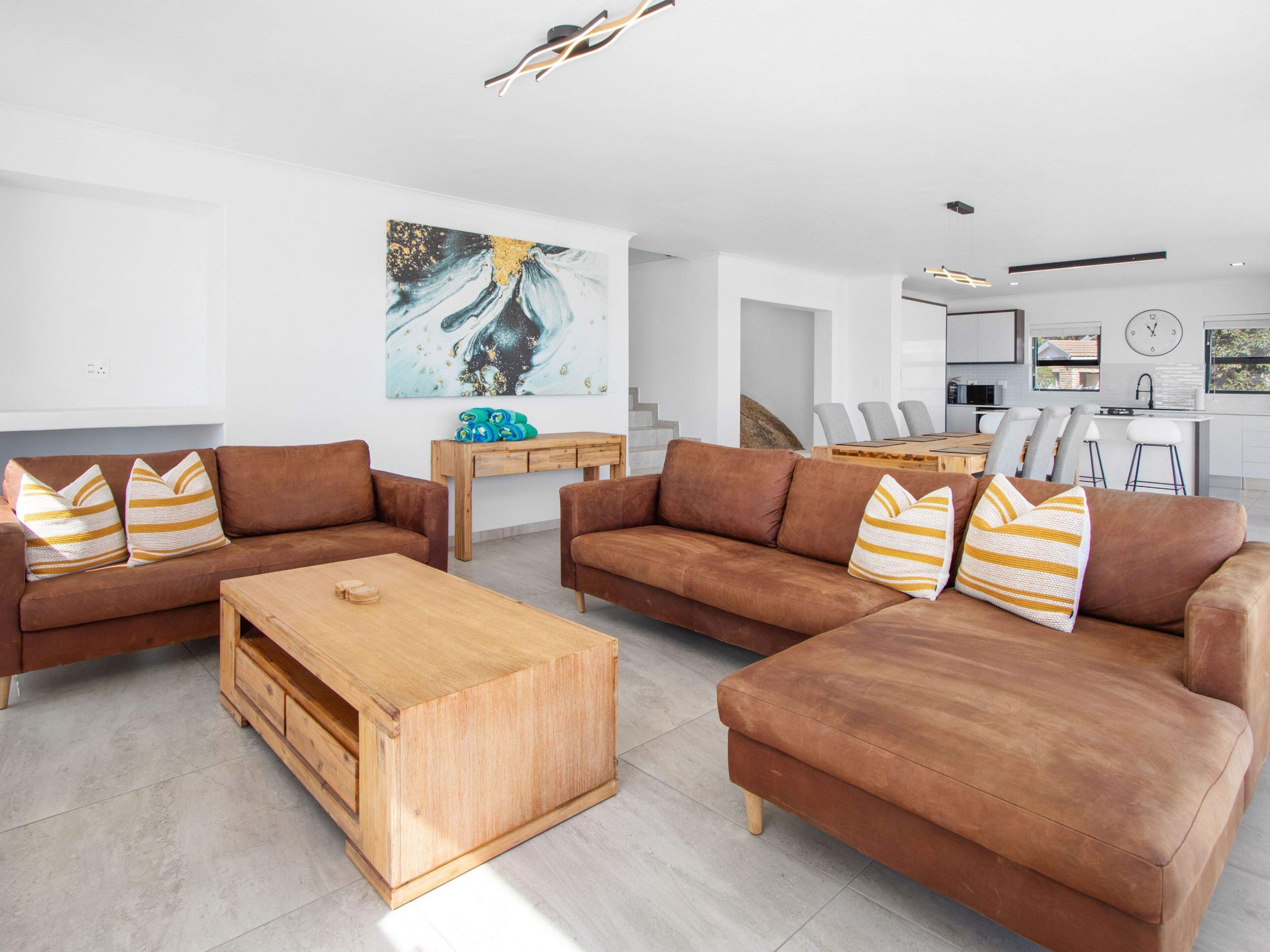Un salon moderne avec des canapés marron, une table basse en bois et un tableau accroché au mur.