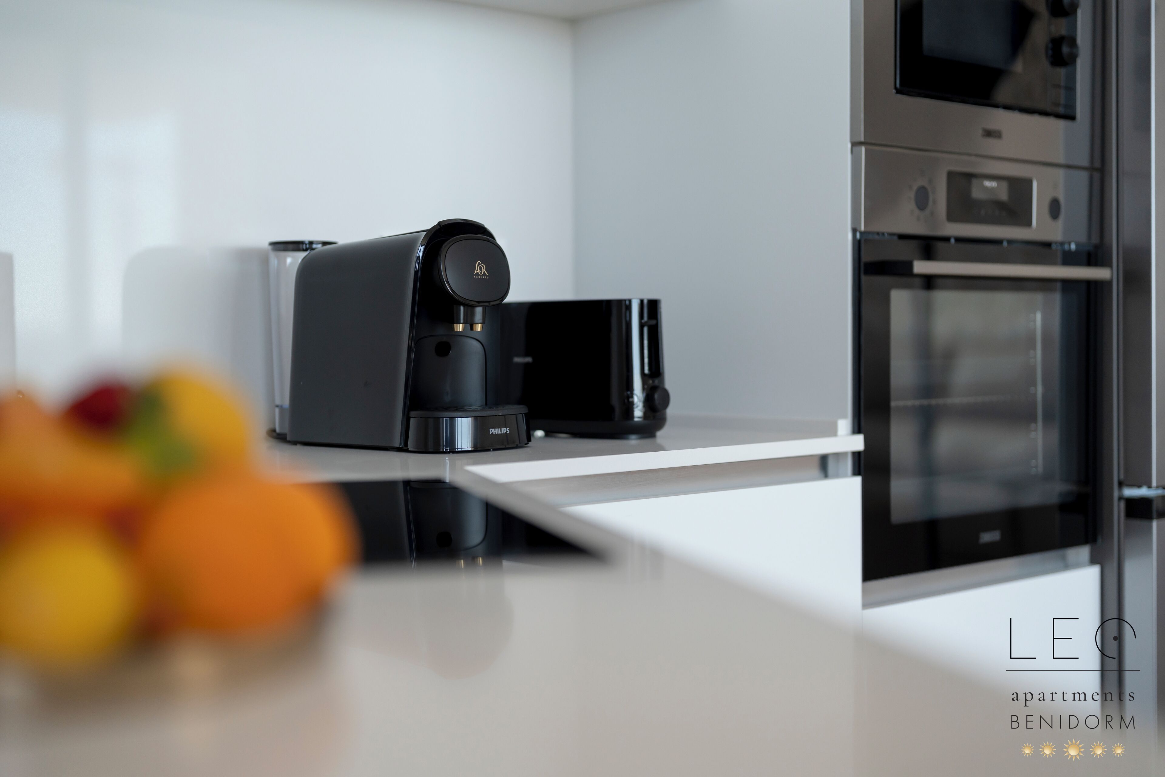Een moderne keuken met een koffiezetapparaat, oven en magnetron.
