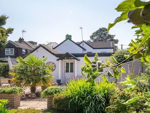 Il s’agit d’une propriété résidentielle dotée d’un jardin bien entretenu, d’un chemin menant à l’entrée et d’une maison blanche avec un toit vert.